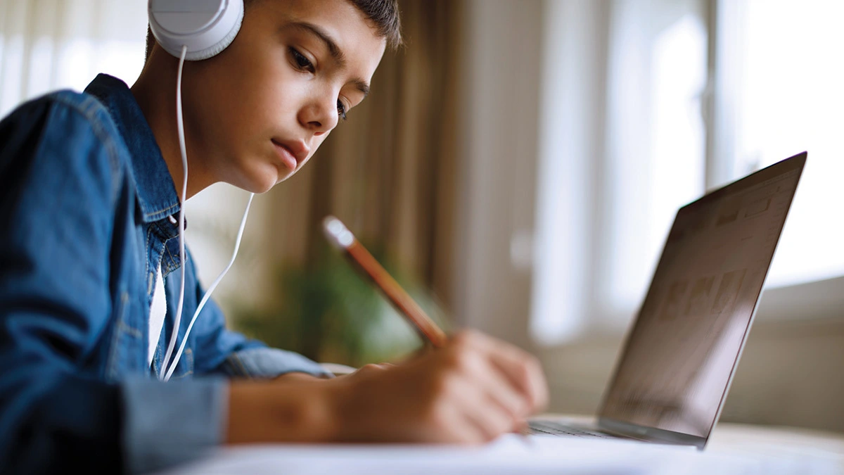 A boy taking notes from a Computer 